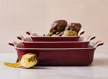 A Rhone red Dutch oven sits on a table in front of a gold framed portrait